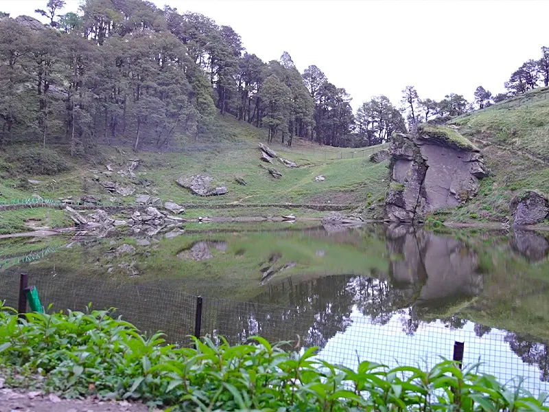 Serolsar Lake Jibhi reflecting clear blue skies in Himachal